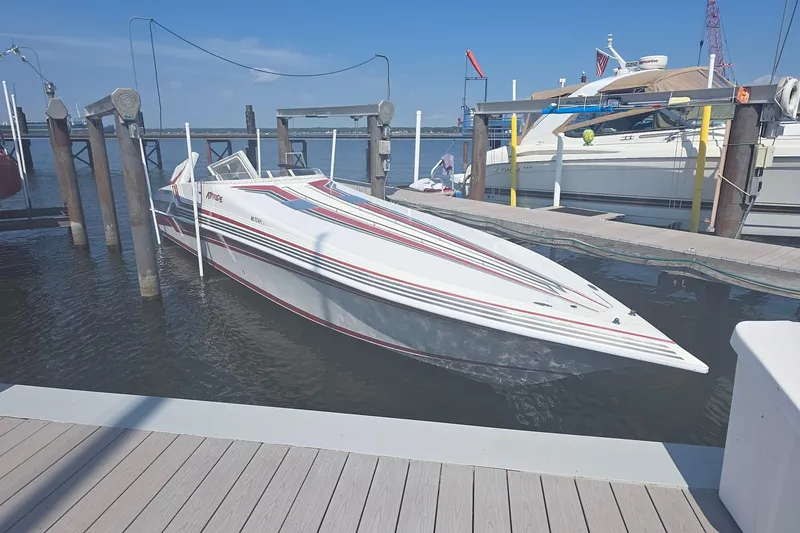 The Image of 1992 Fountain speedboat docked at marina, featuring sleek design and vibrant stripes. - 0