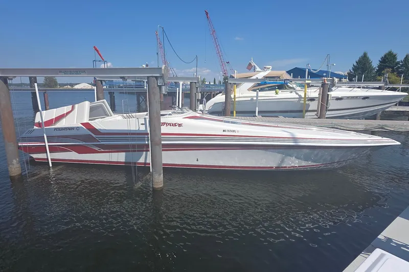 Slide: The Image of 1992 Fountain speedboat docked at marina, featuring sleek red and white design. - 2