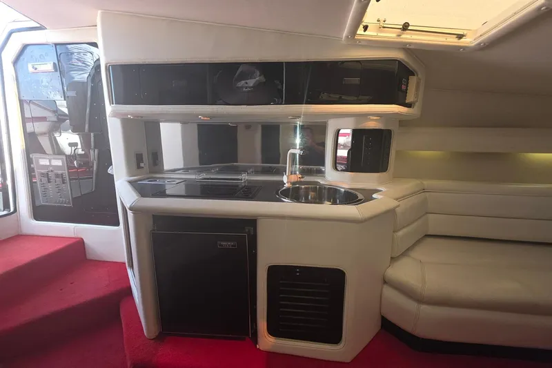 Slide: The Image of Interior of a 1992 Fountain boat featuring a compact kitchen and seating area. - 27