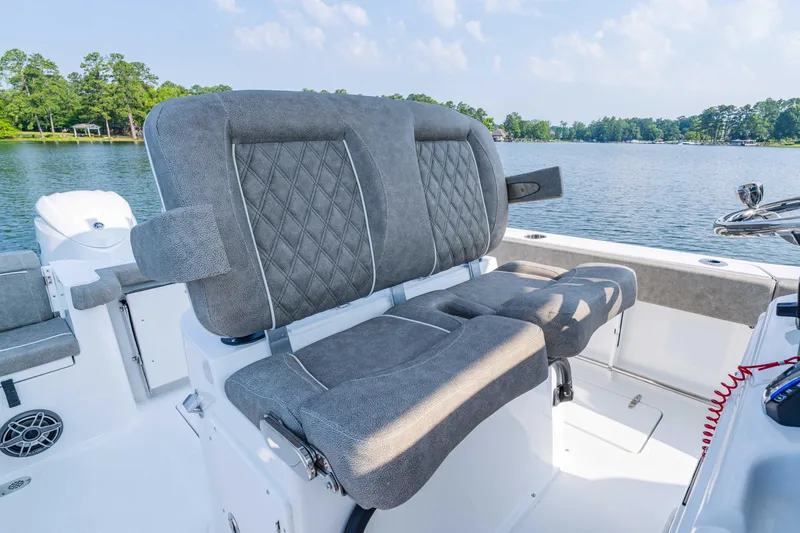 Slide: The Image of 2026 Sea Hunt Gamefish 25 boat interior with plush seating, on a serene lake backdrop. - 11