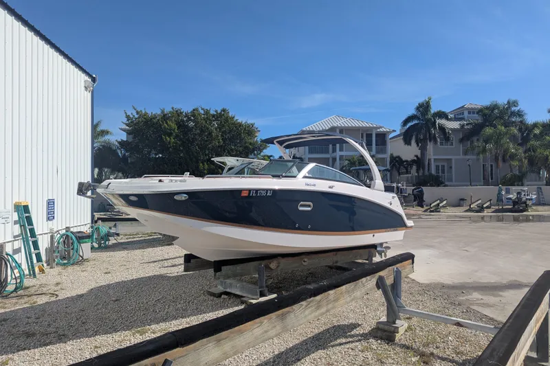 Slide: The Image of 2017 Four Winns HD240 OB boat on a trailer, near a building and palm trees. - 7