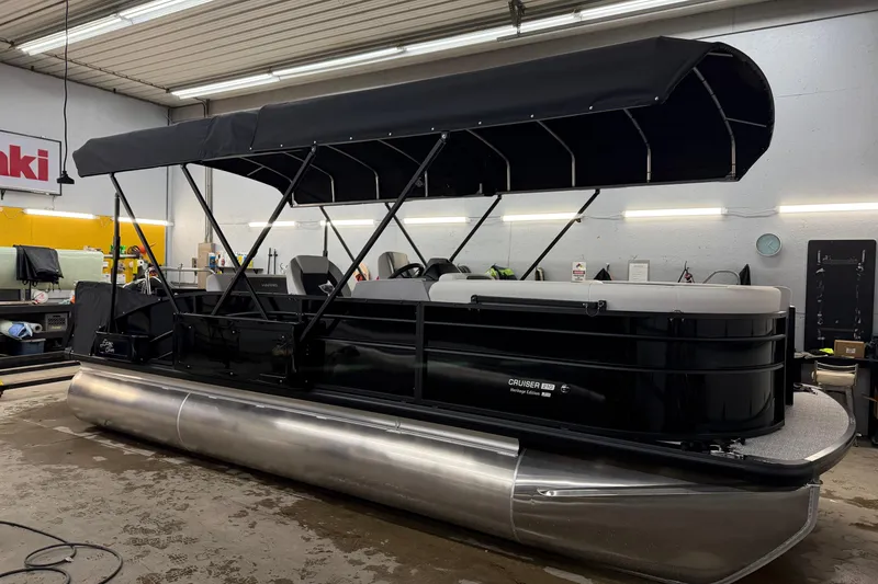 The Image of 2026 Harris Cruiser 210 pontoon boat in a workshop with a black canopy. - 1