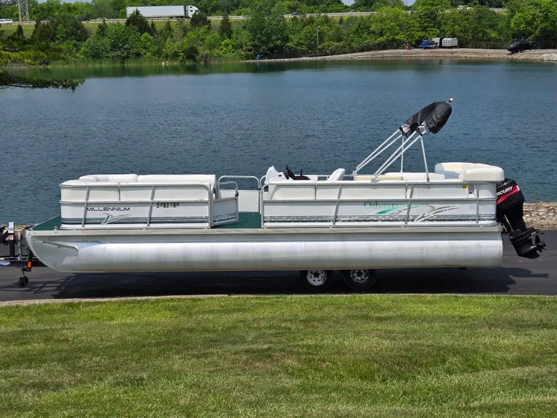 Slide: The Image of 2000 Odyssey Pontoons 2505 Millennium on trailer by a lake. - 0