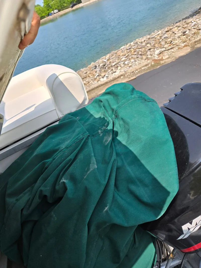 Slide: The Image of Odyssey Pontoons 2505 Millennium boat with green cover, near rocky shoreline. - 17