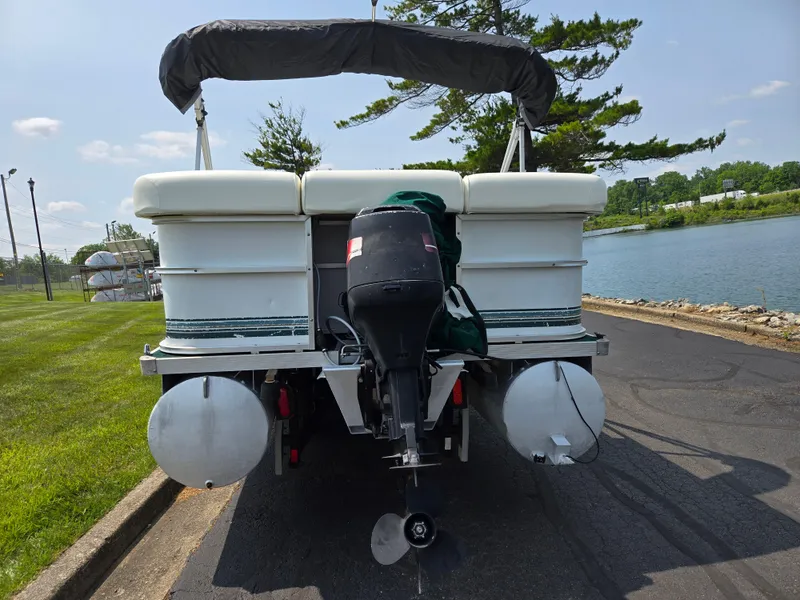 Slide: The Image of 2000 Odyssey Pontoons 2505 Millennium boat with outboard motor, parked by a lakeside road. - 2