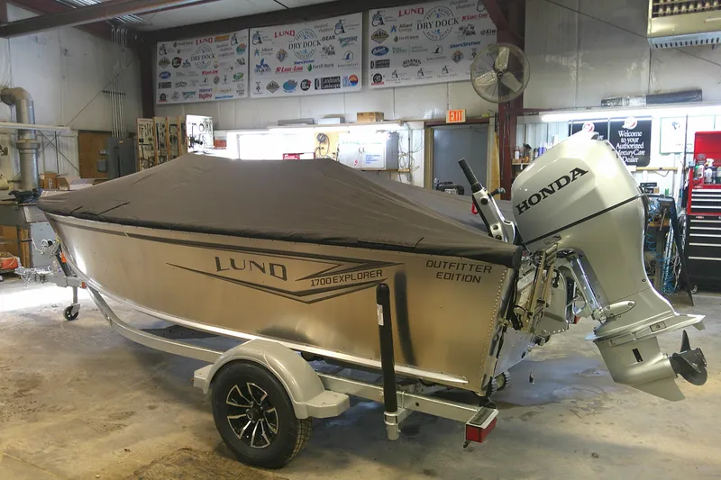 Slide: The Image of 2026 Lund 1700 Explorer Tiller boat with Honda outboard motor in a workshop. - 12