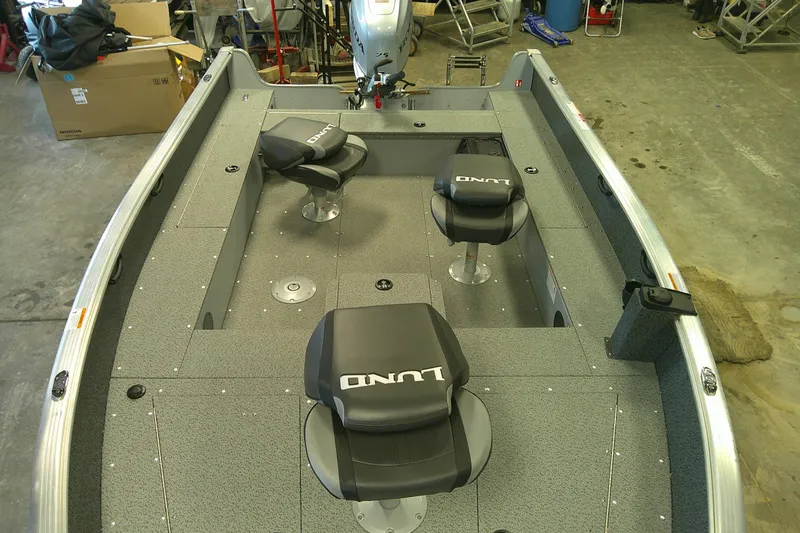 Slide: The Image of 2026 Lund 1700 Explorer Tiller boat interior with seating and motor in a garage. - 8