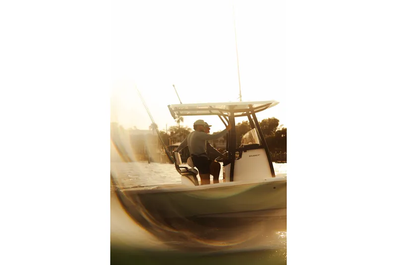 Slide: The Image of Man steering 2026 Sea Hunt BX 22 BR boat at sunset on water. - 3