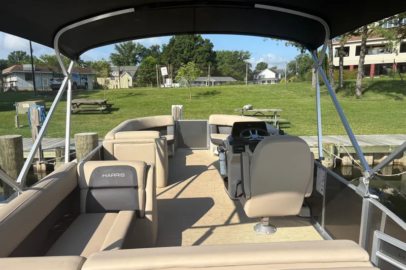 Slide: The Image of 2024 Harris HCX23 pontoon boat interior with seating and steering console. - 2