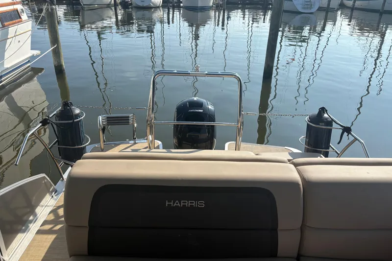 Slide: The Image of 2024 Harris HCX23 boat at marina, rear view with motor and seating. - 6