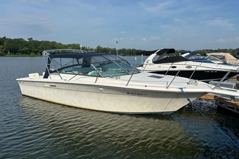 The Image of 1994 Sea Ray 310 Amberjack boat docked on a calm lake under a clear sky. - 0