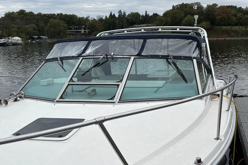 Slide: The Image of 1994 Sea Ray 310 Amberjack boat docked on a calm lake with scenic background. - 15