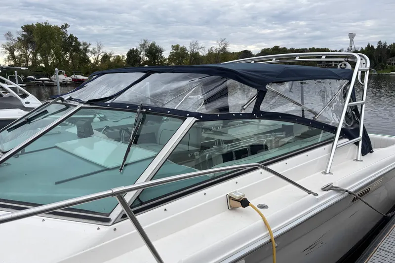 Slide: The Image of 1994 Sea Ray 310 Amberjack boat docked with blue canopy and clear windows. - 17