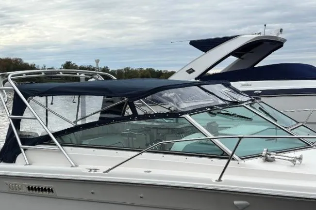 Slide: The Image of 1994 Sea Ray 310 Amberjack boat docked with blue canopy and sleek design. - 18