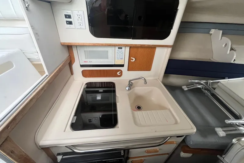 Slide: The Image of Compact kitchen area in a 1994 Sea Ray 310 Amberjack boat with sink and microwave. - 24
