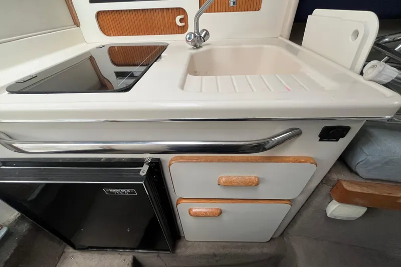 Slide: The Image of 1994 Sea Ray 310 Amberjack kitchen area with sink, stove, and storage drawers. - 25