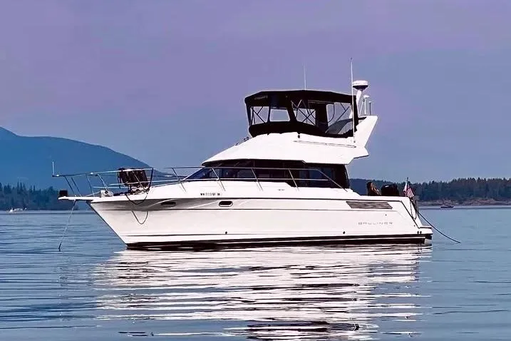 Slide: The Image of 1992 Bayliner 3688 Motoryacht on calm water with scenic mountain backdrop. - 0