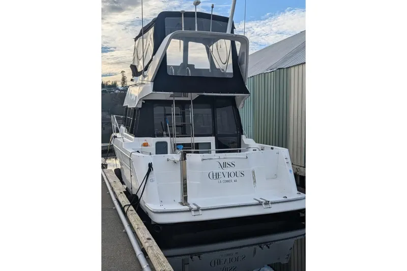 Slide: The Image of 1992 Bayliner 3688 Motoryacht docked, rear view with "Miss Chevious" nameplate. - 2