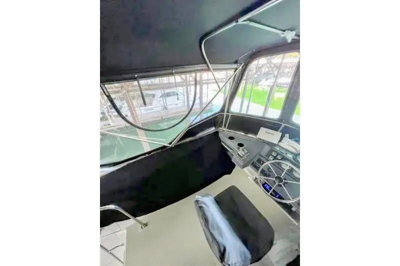 Slide: The Image of 1992 Bayliner 3688 Motoryacht helm with steering wheel and controls, docked in marina. - 29