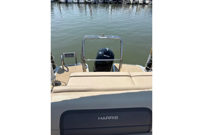 Slide: The Image of 2024 Harris HCX23 boat at dock, rear view with motor and seating. - 10