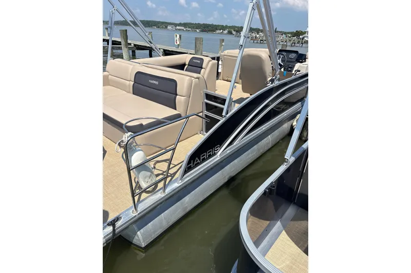 Slide: The Image of 2024 Harris HCX23 pontoon boat docked, featuring beige seating and sleek design. - 4