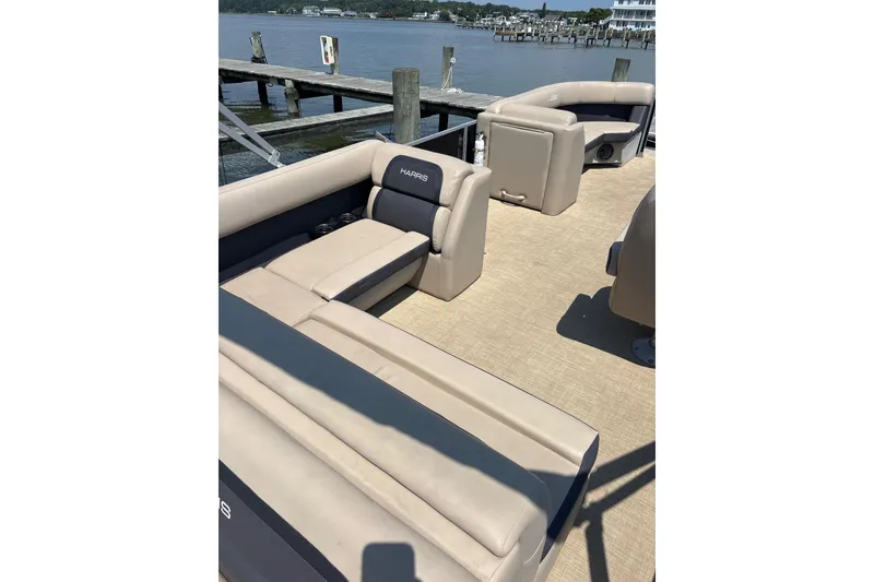 Slide: The Image of 2024 Harris HCX23 pontoon boat interior with beige seating and waterfront view. - 8