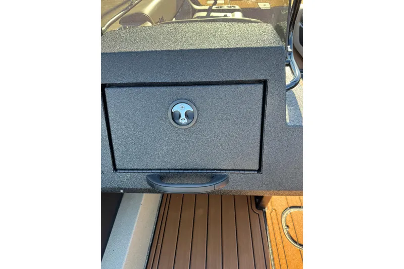 Slide: The Image of 2026 SeaArk Big Easy boat console with secure storage compartment and wood-textured flooring. - 25