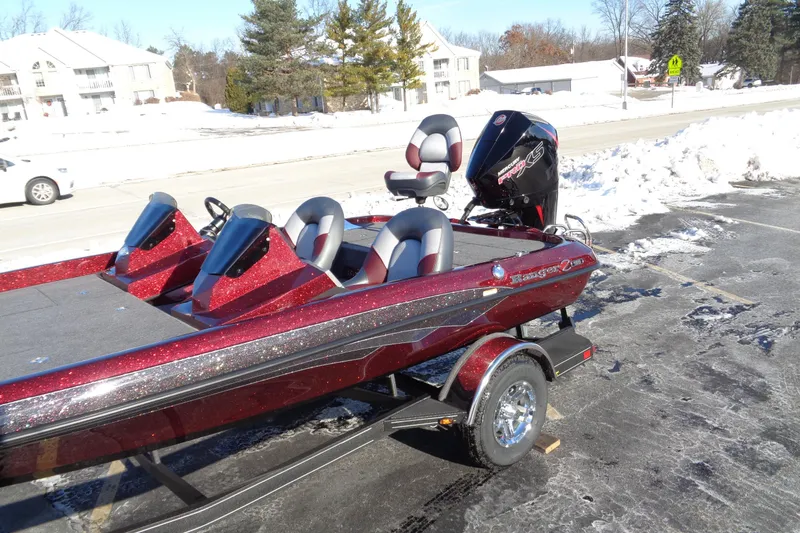 Slide: The Image of 2026 Ranger Z185 boat with red metallic finish parked on snowy pavement. - 11