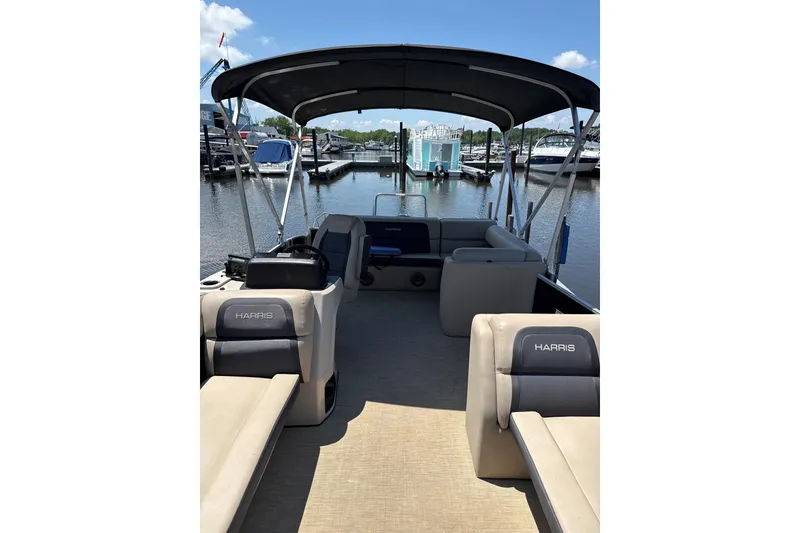 Slide: The Image of 2024 Harris HCX23 pontoon boat interior at marina, featuring comfortable seating and canopy. - 3
