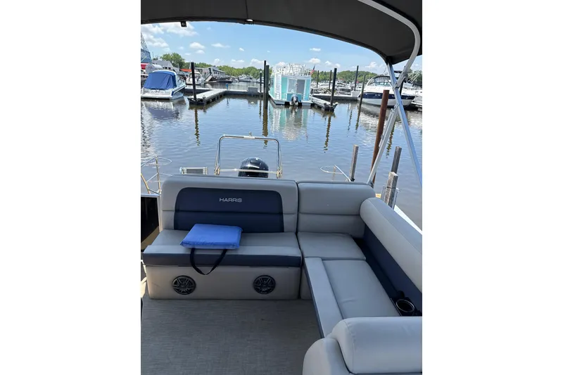 Slide: The Image of 2024 Harris HCX23 pontoon boat interior at marina, featuring comfortable seating and scenic water view. - 8