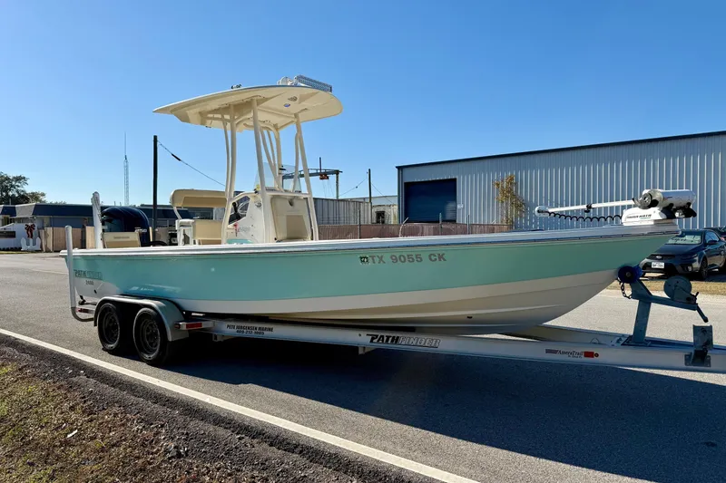 Slide: The Image of 2014 Pathfinder 2400 TRS boat on trailer, parked outdoors near industrial building. - 5