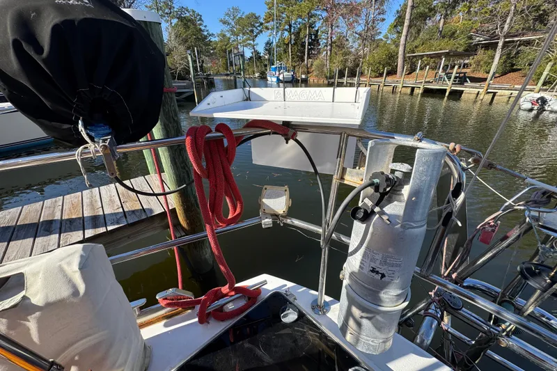 Slide: The Image of Sailboat deck with propane tank and red rope, Creekmore Cutter 1997, docked by wooden pier. - 13