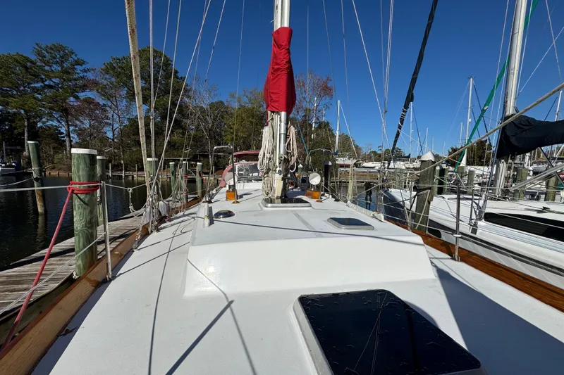 Slide: The Image of Creekmore Cutter 1997 sailboat docked at marina, clear blue sky, surrounded by trees. - 23