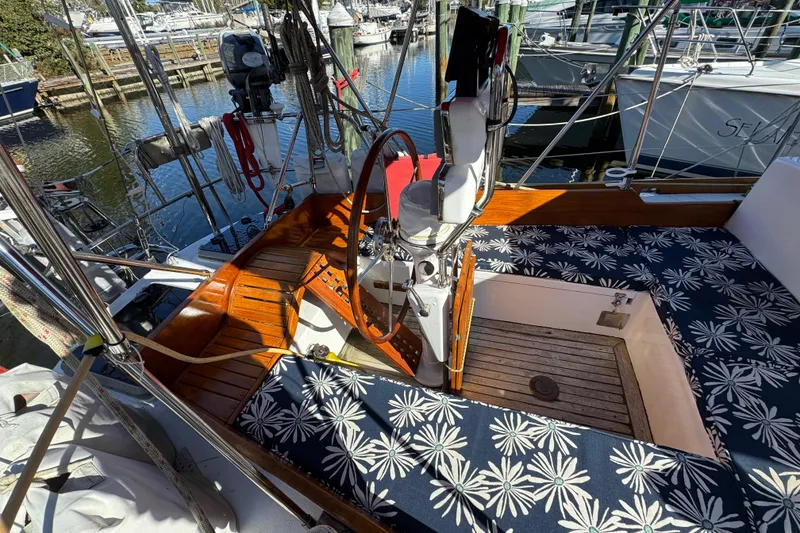 Slide: The Image of 1997 Creekmore Cutter sailboat cockpit with floral cushions and wooden accents at marina. - 27