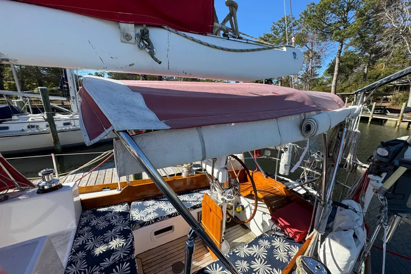 Slide: The Image of Creekmore Cutter 1997 sailboat with red canopy and wooden deck, docked at marina. - 35