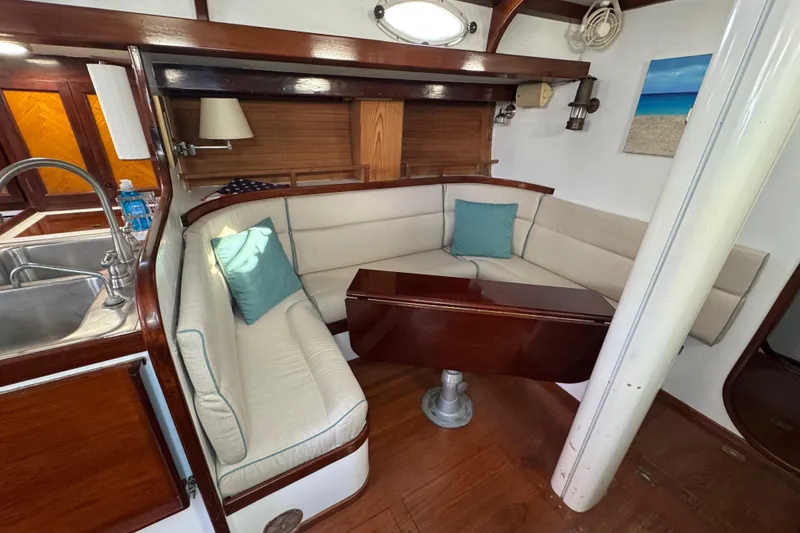 Slide: The Image of Cozy 1997 Creekmore Cutter yacht interior with cushioned seating and wooden table. - 48
