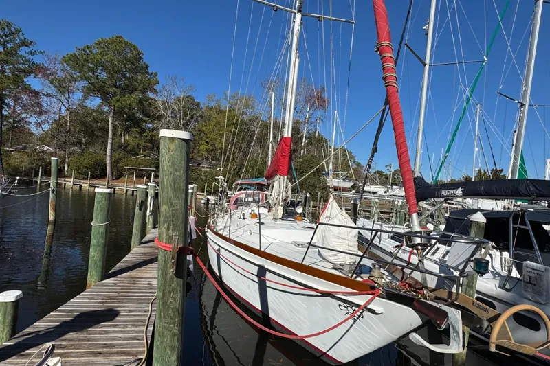 Slide: The Image of Sailboat docked at marina, Creekmore Cutter 1997, with red sail covers and clear blue sky. - 5