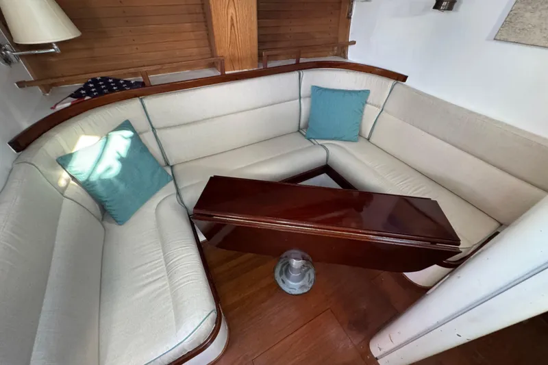Slide: The Image of Cozy 1997 Creekmore Cutter yacht interior with cushioned seating and wooden table. - 51