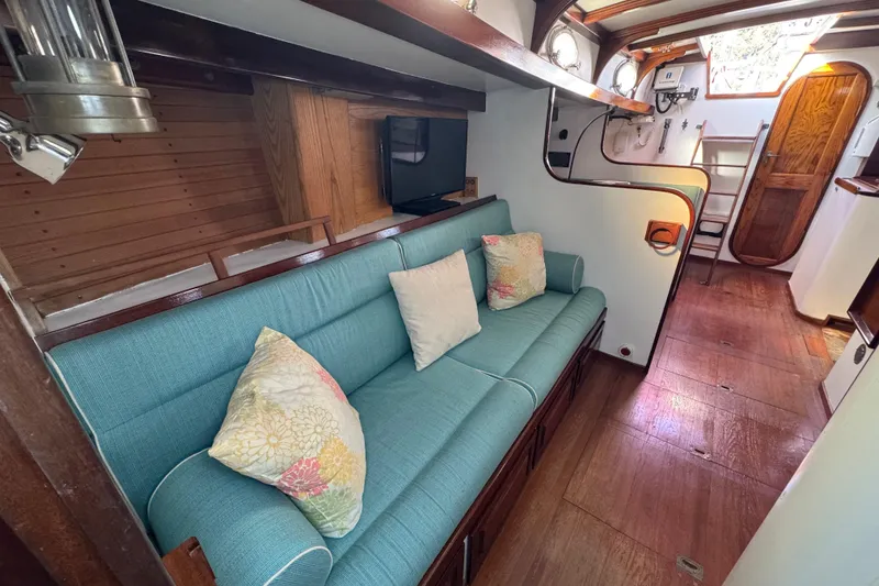 Slide: The Image of Interior of 1997 Creekmore Cutter sailboat with teal sofa and wooden accents. - 62