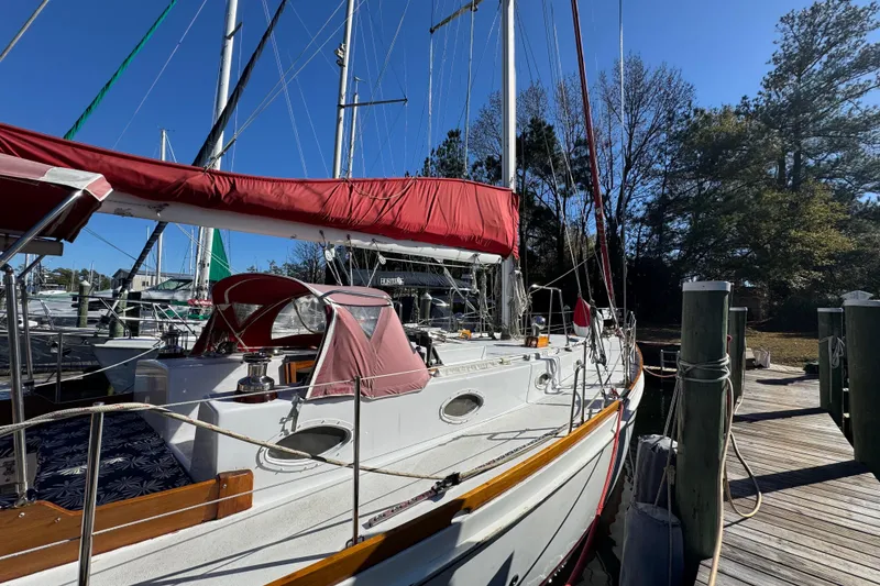 Slide: The Image of Sailboat docked at marina, Creekmore Cutter 1997, with red canopy and clear blue sky. - 8
