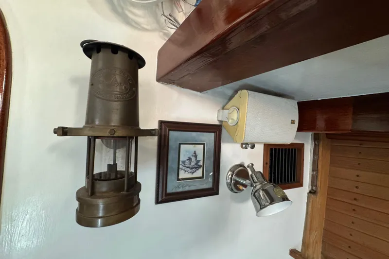 Slide: The Image of Vintage nautical decor inside a 1997 Creekmore Cutter, featuring a brass lantern and framed artwork. - 83