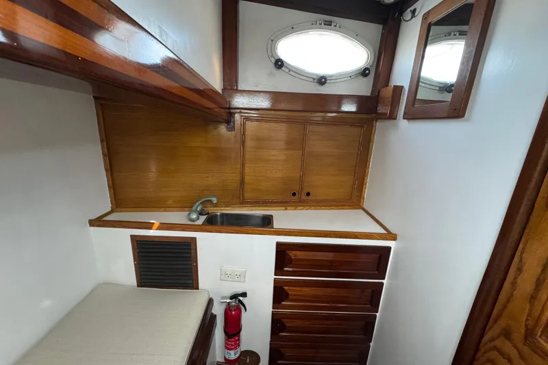 Slide: The Image of 1997 Creekmore Cutter interior with wooden cabinetry, sink, and porthole window. - 88