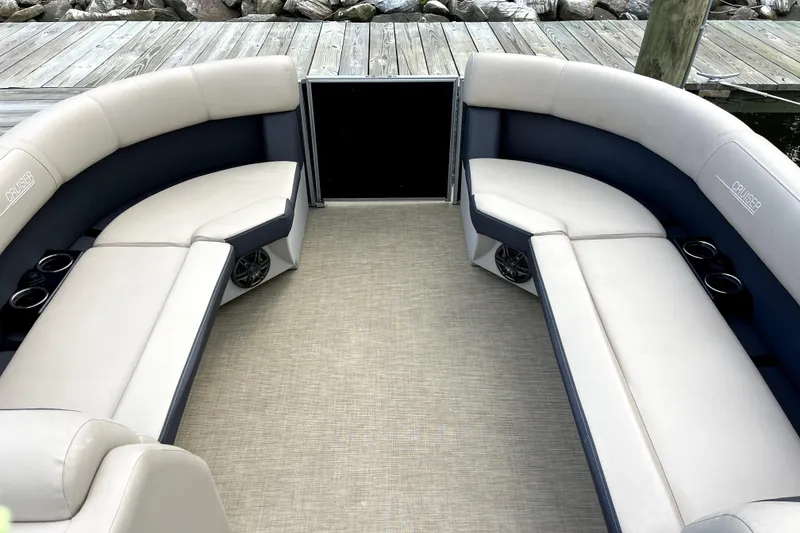 Slide: The Image of 2024 Harris HCX23 boat interior with beige seating and cup holders on a dock. - 6