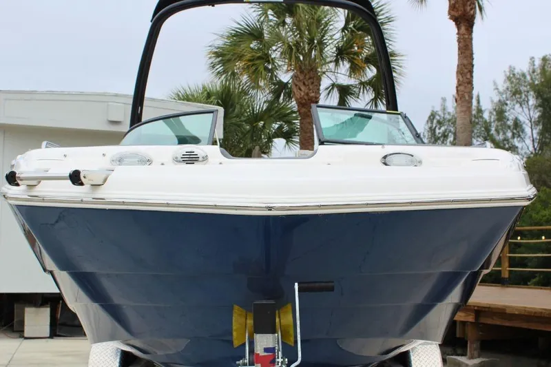 Slide: The Image of 2023 NauticStar 243 DC Deck boat, blue hull, docked with palm trees in background. - 5