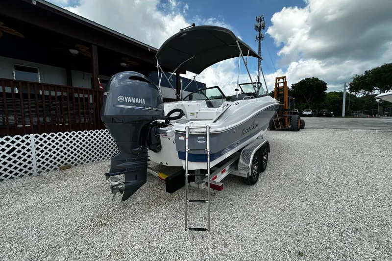 Slide: The Image of 2024 NauticStar 203 DC Deck boat with Yamaha engine on trailer, parked outdoors. - 18