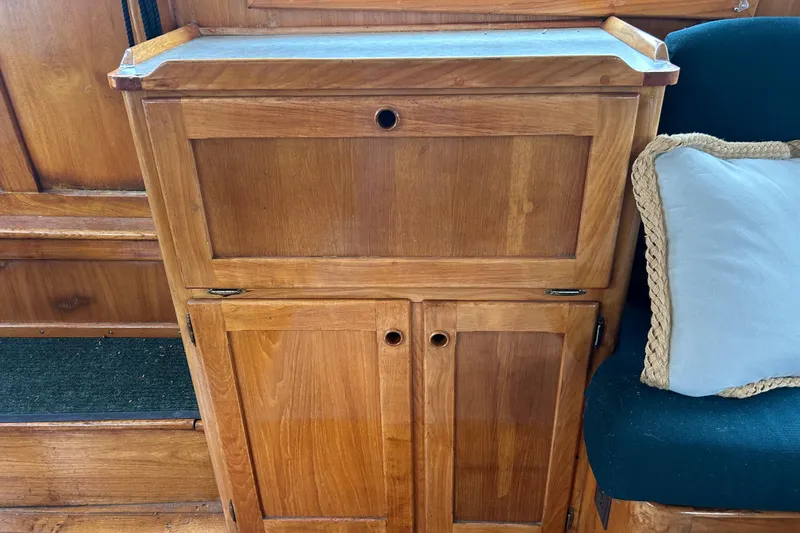 Slide: The Image of Wooden cabinet on a 1976 Bristol Trawler, featuring a blue cushion. - 10