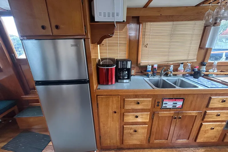 Slide: The Image of 1976 Bristol Trawler kitchen with stainless steel fridge, wooden cabinets, and dual sink. - 13
