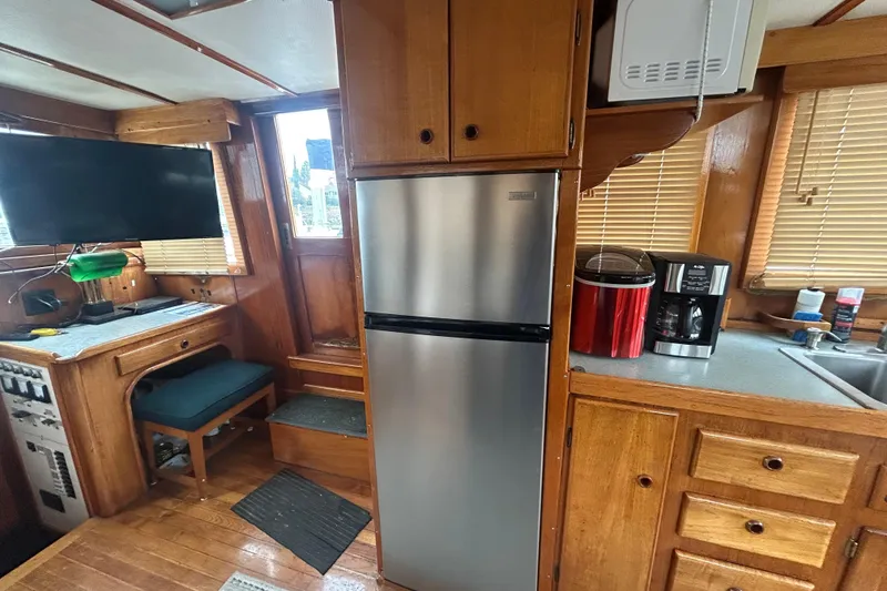 Slide: The Image of 1976 Bristol Trawler interior with wooden cabinetry, stainless steel fridge, and modern appliances. - 16