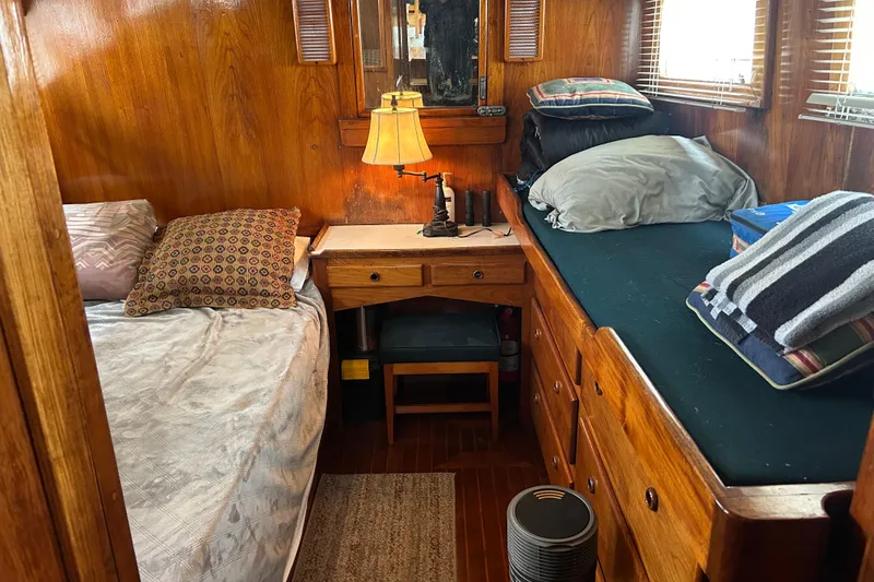 Slide: The Image of 1976 Bristol Trawler cabin interior with wooden decor, twin beds, and a small desk. - 24