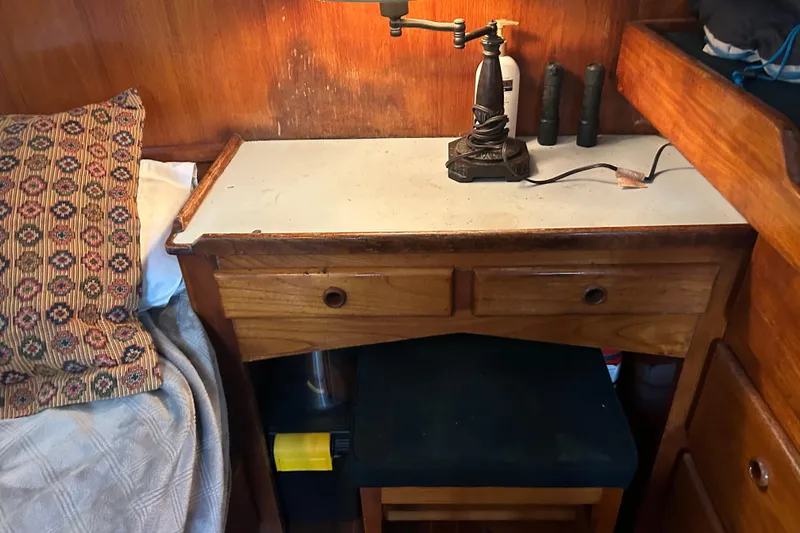 Slide: The Image of 1976 Bristol Trawler cabin interior with wooden desk, vintage lamp, and patterned pillow. - 28